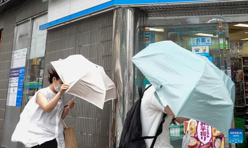 Pedestrians walk in the rain along a street in Tokyo, Japan, Sept. 19, 2022. Two people were reported dead and another missing on Monday after powerful typhoon Nanmadol landed in Japan's southwestern region of Kyushu, bringing rain and gales, local media reported. (Xinhua/Zhang Xiaoyu)