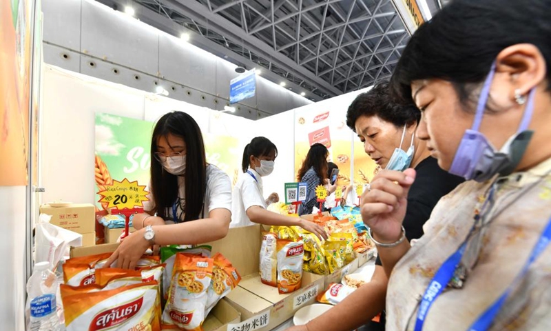 Visitors buy Thai snacks during the 19th China-ASEAN Expo in Nanning, capital of south China's Guangxi Zhuang Autonomous Region, Sept. 18, 2022. The 19th China-ASEAN Expo, scheduled for Sept. 16 to 19 in Nanning, has attracted a total of 1,653 enterprises to its offline event. A wide range of featured commodities from ASEAN countries have caught visitors' eyes during the expo. (Xinhua/Huang Xiaobang)


