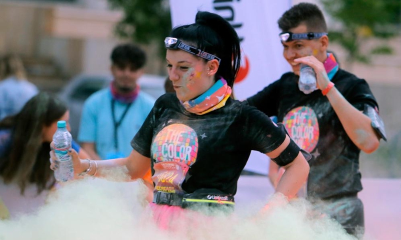 Runners are sprayed with colored powder during the Color Run Night fun race in Bucharest, capital of Romania, Sept. 17, 2022.Photo:Xinhua