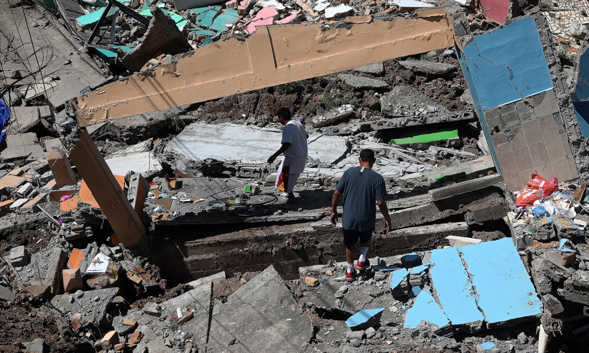 Locals walk among the rubble at the Guillen neighborhood, in northeast Tegucigalpa, Honduras, on September 18, 2022, following a chain of landslides which destroyed dozens of houses due to a geological fault, activated by heavy rains hitting the capital. Photo: AFP