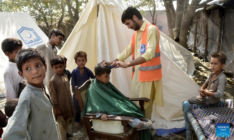 A flood-affected boy gets a haircut at a makeshift camp in Charsadda, Pakistan, on Sept. 21, 2022. The total death toll in Pakistan from this season's monsoon rains and floods since mid-June has risen to around 1,569, along with 12,860 injured, the National Disaster Management Authority (NDMA) said.(Photo: Xinhua)