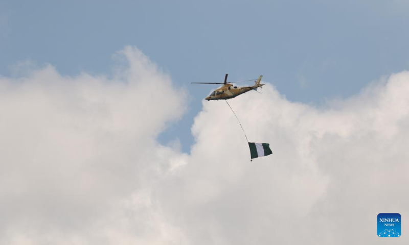 A helicopter carries a Nigerian national flag during celebrations marking Nigeria's Independence Day in Abuja, Nigeria, Oct. 1, 2022. (Photo by Emma Houston/Xinhua)