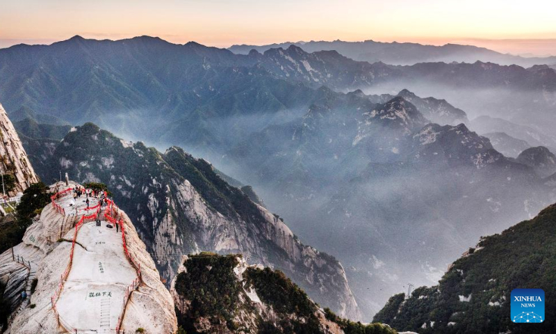 Aerial photo taken on Sept. 25, 2022 shows people visiting Mount Huashan at sunset in northwest China's Shaanxi Province. (Xinhua/Tao Ming)