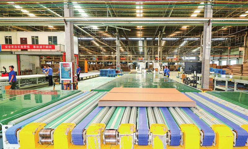 Employees work on a green manufacturing assembly line at a new materials firm in Dongyang, East China's Zhejiang Province on September 25, 2022. It was opening day for the assembly line, with an annual production capacity of 100 million square meters of corrugated board. The factory's products will cut fossil fuel consumption and reduce pollution.    Photo: cnsphoto