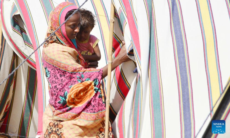 A woman holding a kid enters a makeshift shelter on the outskirts of southern Pakistan's Hyderabad on Sept. 24, 2022.Photo:Xinhua