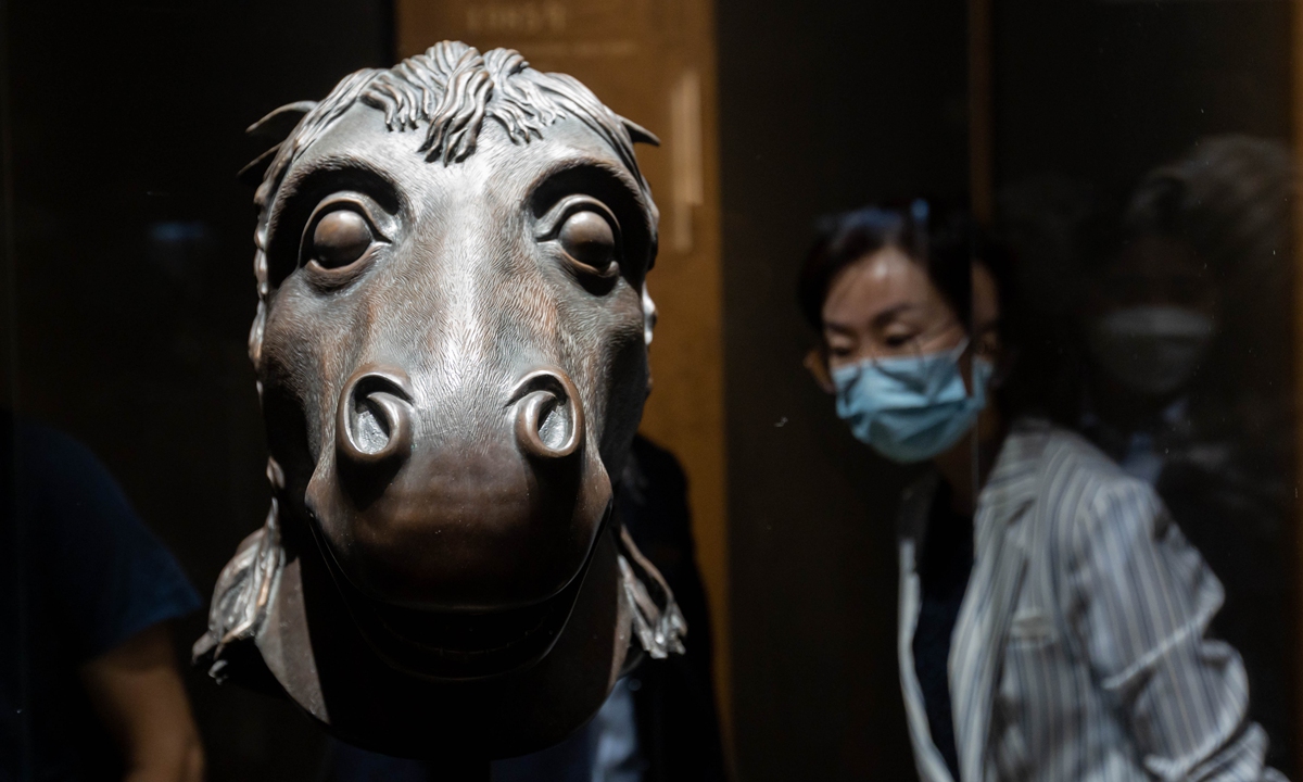 A visitor appreciates a bronze horse head sculpture at an exhibition of lost cultural relics from Beijing's Old Summer Palace, or Yuanmingyuan