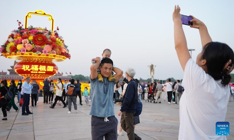 Tourists pose for photos in front of a flower basket at Tian'anmen Square in Beijing, capital of China, Sept. 25, 2022. The 18-meter-tall display in the shape of a flower basket is placed at Tian'anmen Square as a decoration for the upcoming National Day holiday.(Photo: Xinhua)