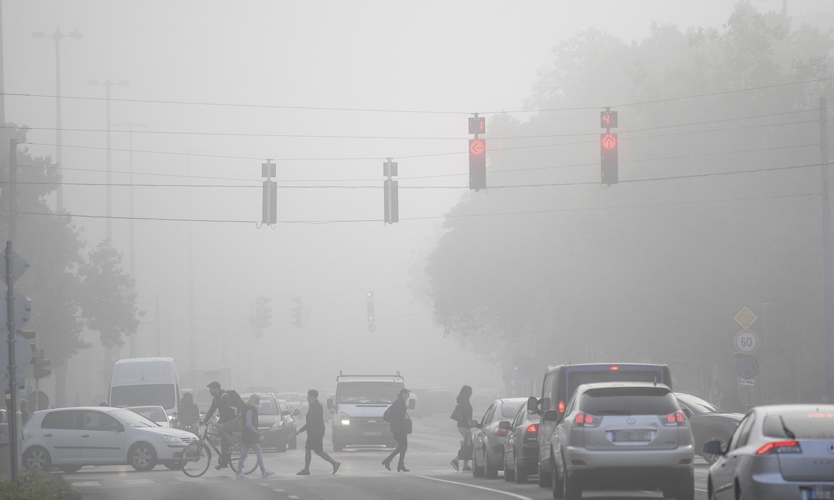 Pedestrians cross the road amid dense fog in Debrecen, Hungary, on September 27, 2022. Photo: VCG