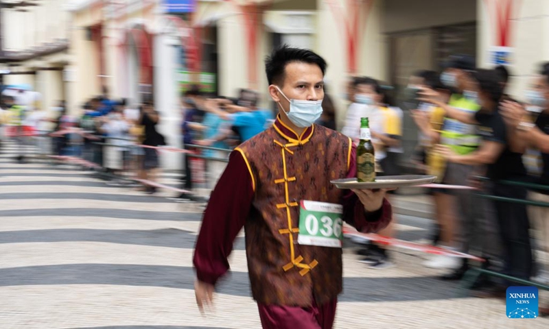 A participant takes part in a tray race marking the World Tourism Day in Macao, south China, Sept. 27, 2022. A tray race was held in Macao to mark the World Tourism Day on Tuesday. About 130 participants from the local catering and tourism industries took part in the race covering a distance from the Ruins of St. Paul's to the Senado Square. (Photo: Xinhua)