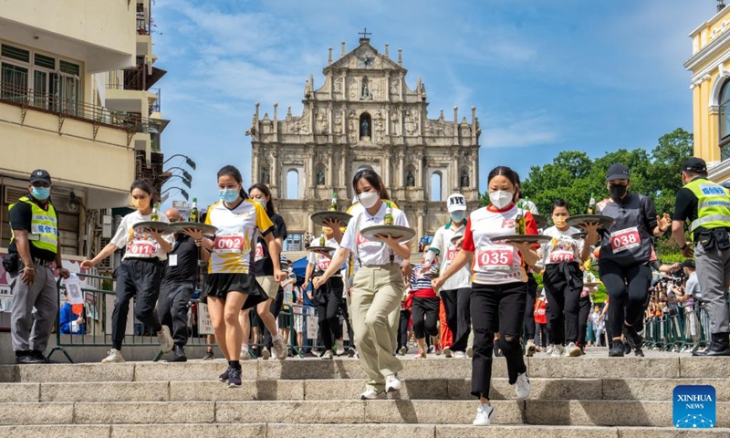 Participants take part in a tray race marking the World Tourism Day in Macao, south China, Sept. 27, 2022. A tray race was held in Macao to mark the World Tourism Day on Tuesday. About 130 participants from the local catering and tourism industries took part in the race covering a distance from the Ruins of St. Paul's to the Senado Square.(Photo: Xinhua)