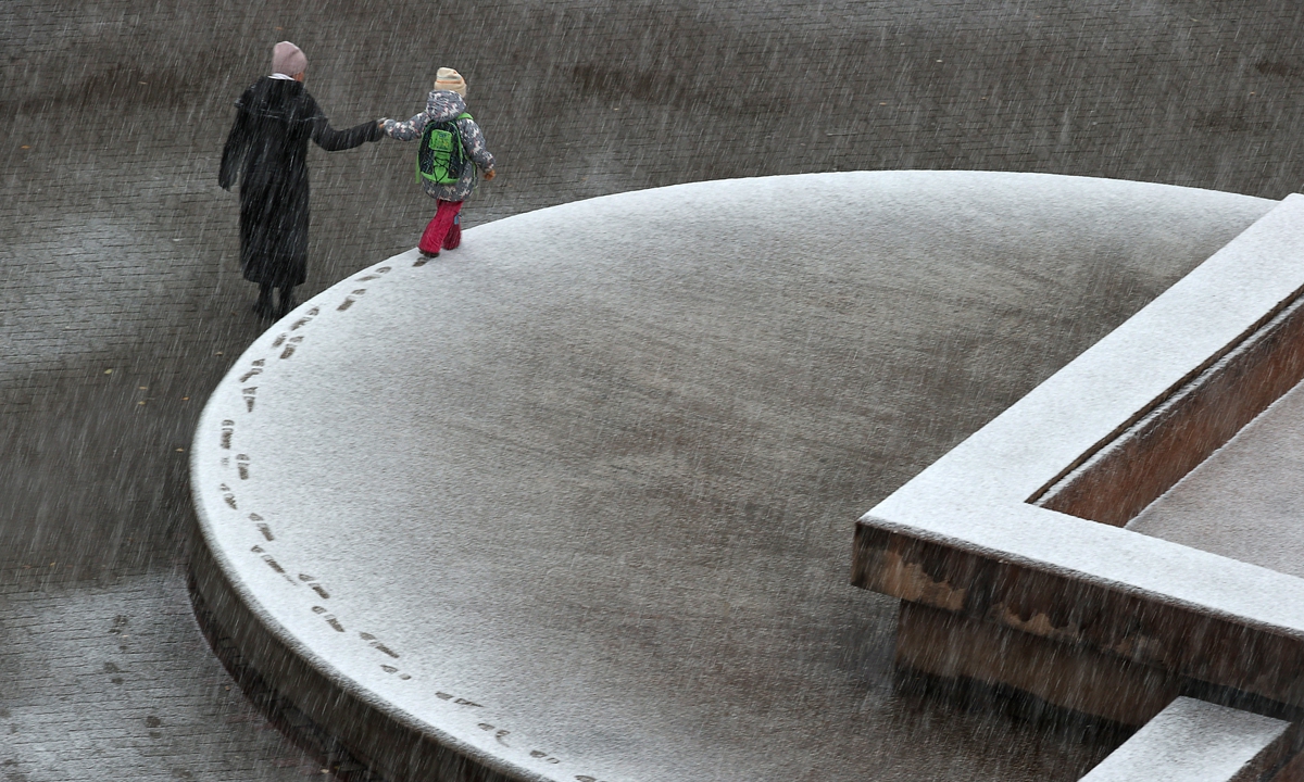 A woman and a child walk during a snowfall on September 29, 2022, in Bratsk, Russia. Photo: VCG