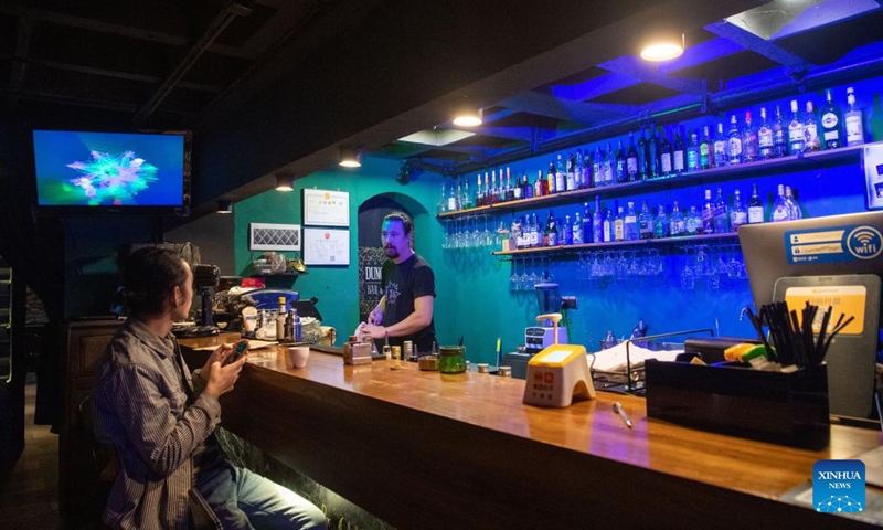 Serbian Bon Scott (R) serves a client at a bar reconstructed from a basement of a former industrial site, in Yuzhong District, southwest China's Chongqing, Sept. 23, 2022.Photo:Xinhua