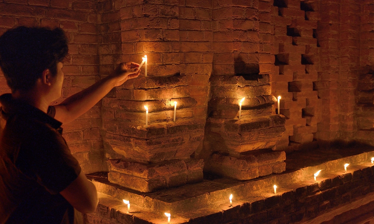 A Buddhist devotee lights candles at the Shwe Mann Temple in Myanmar on October 8, 2014. Photo: AFP