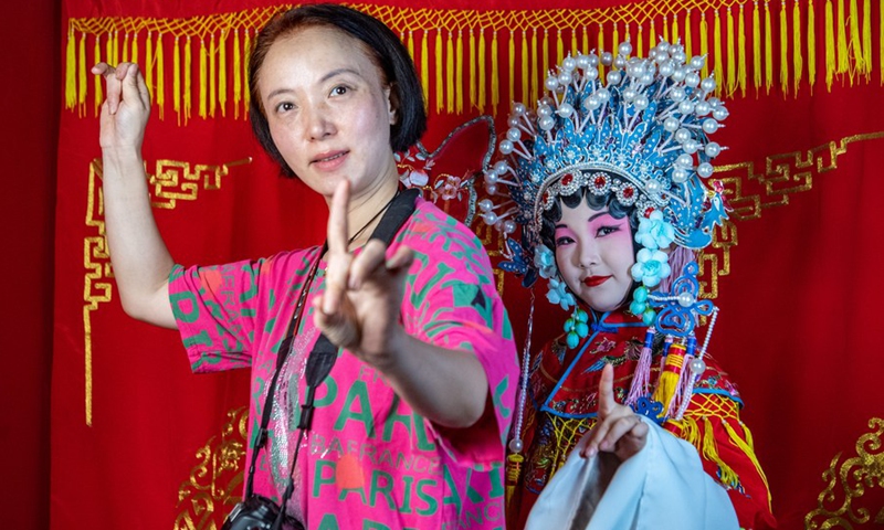 A child dressed in Chuanju (Sichuan opera) costume poses for photos under the guidance of a staff member in Ciqikou ancient town, southwest China's Chongqing Municipality, Oct. 2, 2022.(Photo: Xinhua)