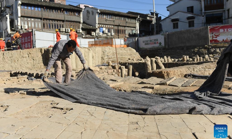 A staff member covers the foundation of an ancient building at the archaeological site of Shuomen ancient port in Wenzhou, east China's Zhejiang Province, Oct. 10, 2022. The archaeological site of Shuomen ancient port was discovered at the end of 2021, with ruins of ancient buildings, shipwrecks, and porcelain pieces unearthed in the following archaeological excavations.(Photo: Xinhua)