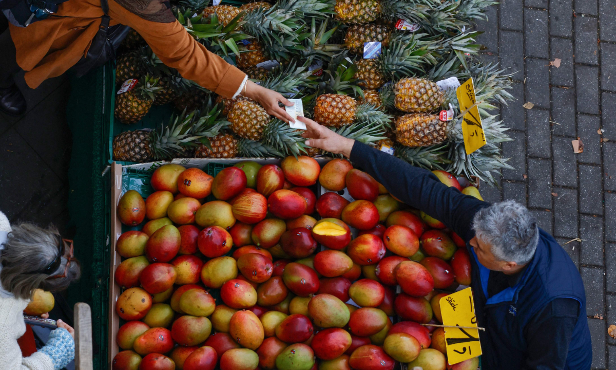 A shopper buys pineapples at a fruit and vegetable market in Berlin on October 14, 2022. Inflation will hit 8 percent in 2022 and 7 percent in 2023, the German government forecast. The government recently unveiled a 200-billion-euro fund to shield consumers and businesses from surging prices, which includes a cap on energy costs. Photo: VCG