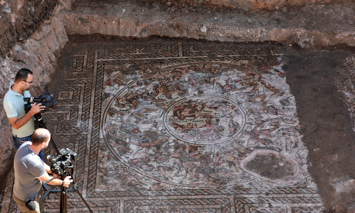 Photographers take pictures of a mosaic floor dating to the Roman era being excavated in the city of Al-Rastan in Syria’s west-central province of Homs on October 12, 2022, after its discovery was announced by Syria’s General Directorate of Antiquities. Photo: AFP