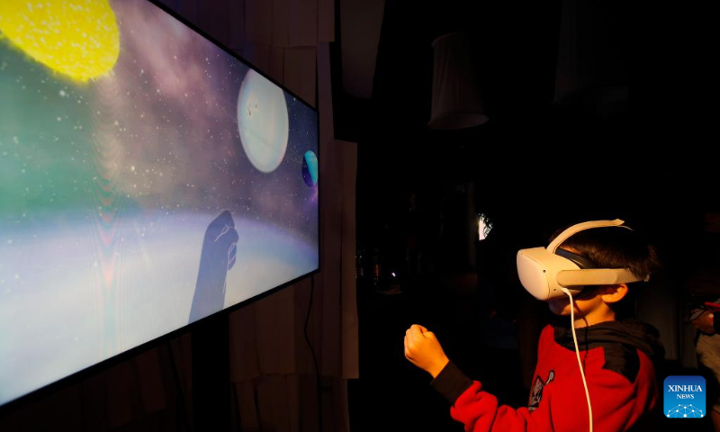 A boy experiences virtual reality goggles while visiting the 3rd edition of the new media art festival RADAR in Bucharest, capital of Romania, Oct. 16, 2022. (Photo by Cristian Cristel/Xinhua)