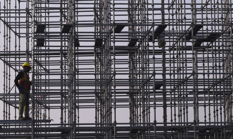 A worker fixes bolts on a steel scaffolding at a construction site for the upcoming coastal road project in Mumbai on January 3, 2022. Photo: VCG