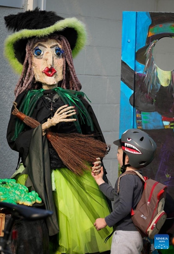 A child takes a look at a scarecrow displayed on a street ahead of Halloween in Vancouver, British Columbia, Canada, on Oct. 17, 2022.(Photo: Xinhua)