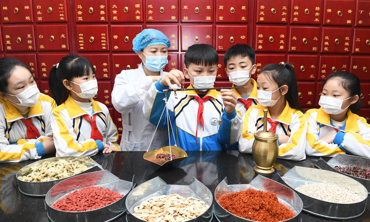 Pupils experience weighing traditional Chinese medicine (TCM) at a TCM store in Shijiazhuang, North China's Hebei Province, on October 20, 2022. The World Traditional Medicine Day falls on October 22, 2022. The practice of TCM has spread to 196 countries and regions, and China has signed specialized cooperation agreements on TCM with over 40 countries, regions and international organizations. Photo: CFP