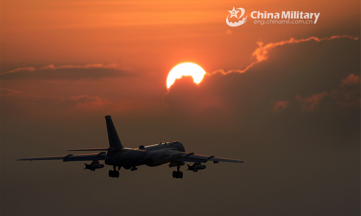 An aircraft flies through dense clouds under the setting sun. Photo:China Military