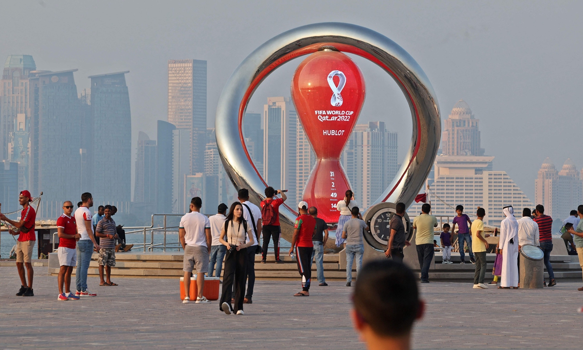 People walk past the Qatar 2022 FIFA World Cup countdown clock as it approaches thirty days before the sporting event, in Doha on October 20, 2022.Photo:VCG