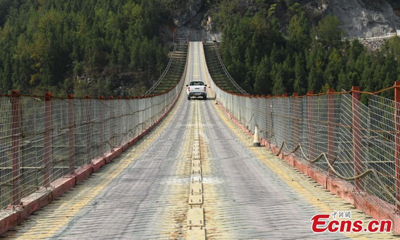 2022年10月25日，一辆卡车在中国西南部重庆市武隆市一座300米高的悬索链桥上行驶。（照片：中新社/周毅）