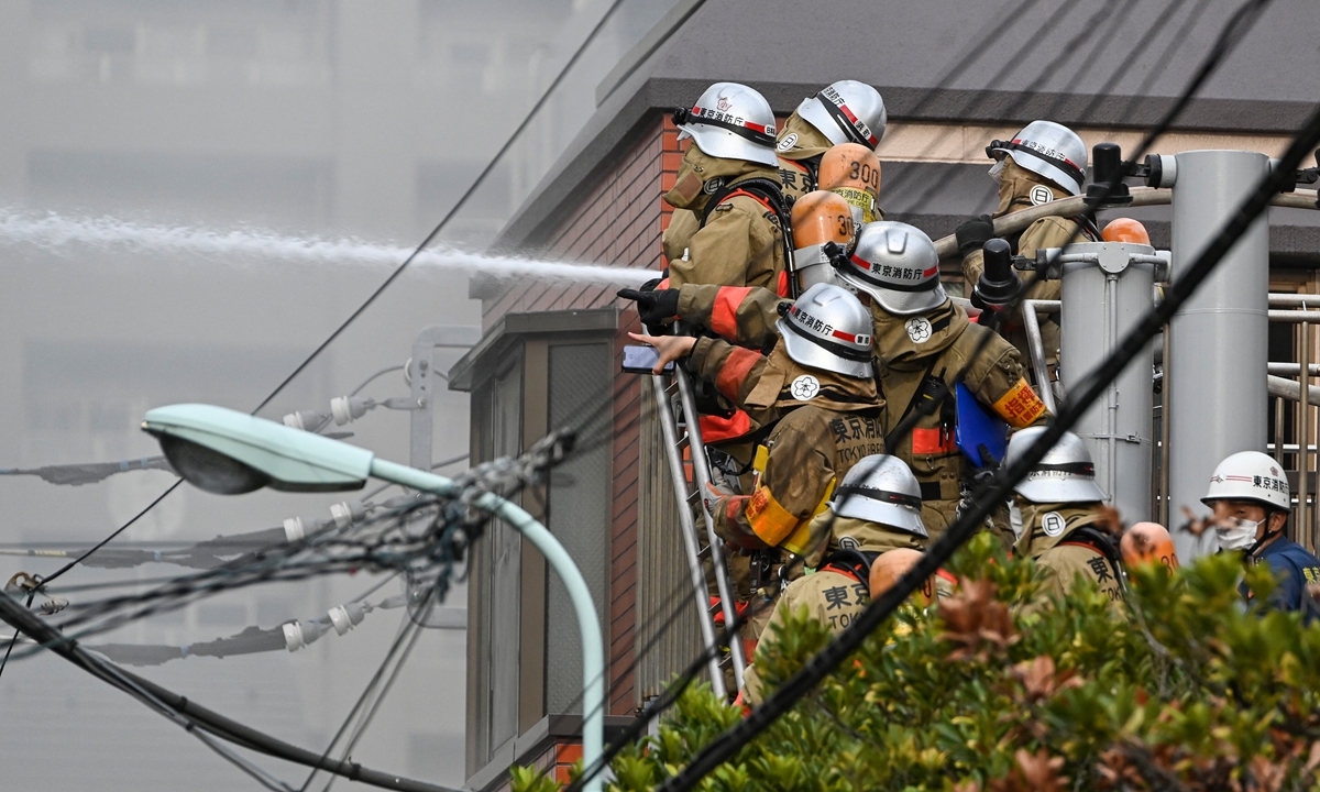 Firefighters work outside of a building where a fire broke out in Tsukishima district of Tokyo, Japan, on October 27, 2022. Photo: AFP