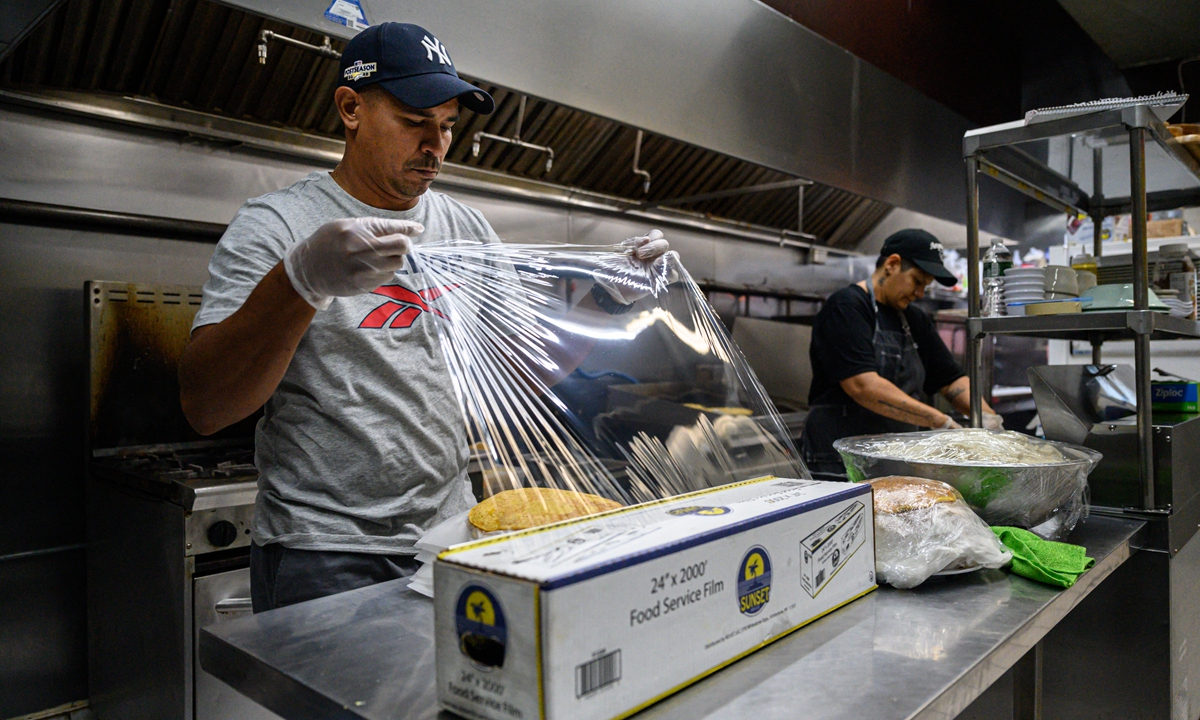 Gustavo Mendez (left) prepares food at the restaurant where he works, in the Queens borough of New York City, on October 18, 2022. Photo: AFP