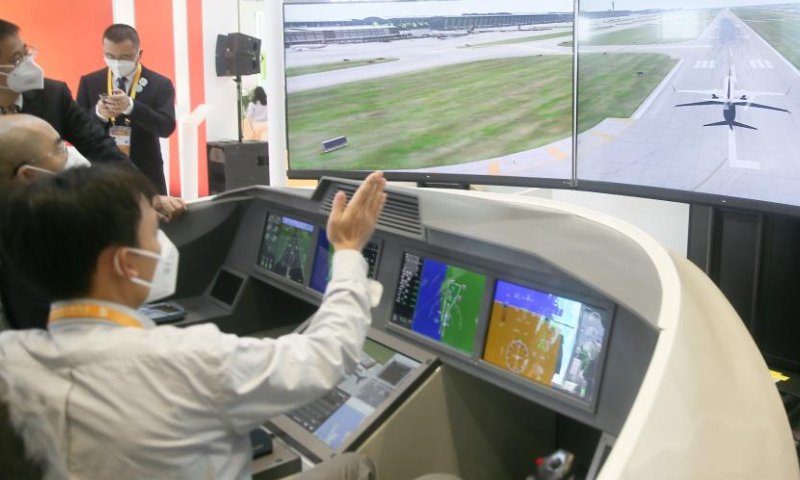 A staff member instructs as a visitor tries a flight simulator at the Honeywell booth at the Intelligent Industry & Information Technology Exhibition Area of the fifth China International Import Expo (CIIE) at the National Exhibition and Convention Center (Shanghai) in east China's Shanghai, Nov. 5, 2022. The fifth CIIE is scheduled on Nov. 5-10 in China's economic hub Shanghai. Photo: Xinhua