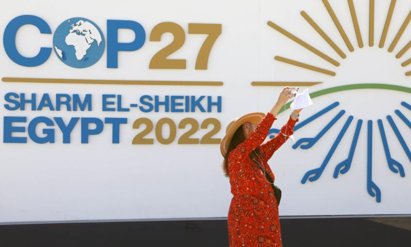 A woman takes pictures in front of a display board of the 27th Conference of the Parties of the United Nations Framework Convention on Climate Change (COP27) in Sharm El-Sheikh, Egypt, Nov. 6, 2022. The COP27 opened on Sunday in Egypt's coastal city of Sharm El-Sheikh in hopes to turn global climate finance pledges into action. Photo: Xinhua