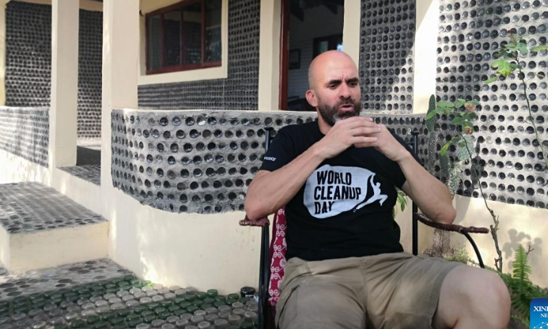 Mozambican environmentalist Carlos Serra shares the story and idea of his glass-bottle house in front of the camera in Macaneta, Mozambique on Nov. 5, 2022. Macaneta, an underdeveloped beach resort located on the northern outskirts of Mozambique's capital Maputo, may be less known to foreign visitors. However, one new project has recently been added to the resort's few attractions: a house built with recycled glass bottles. Photo: Xinhua