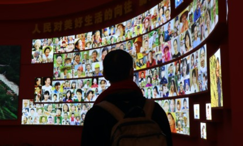 A student from Taiwan looks up at photos in a visit to 