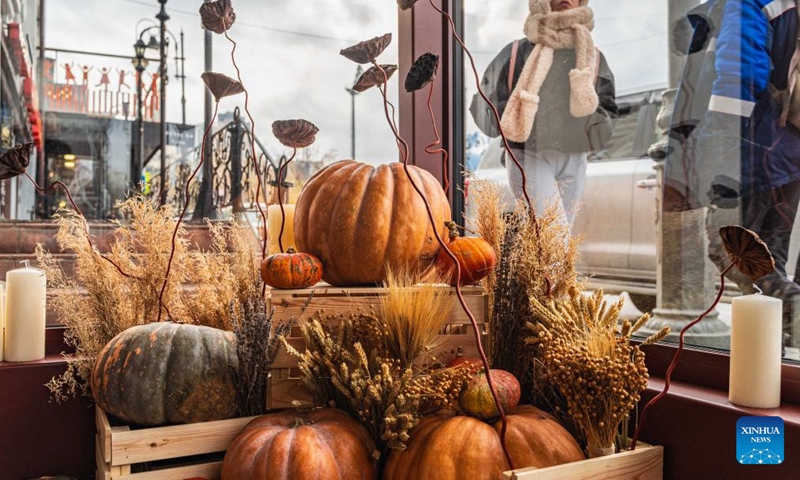 Pedestrians walk by a window decorated with pumpkins in Vladivostok, Russia, Oct. 31, 2022.(Photo: Xinhua)
