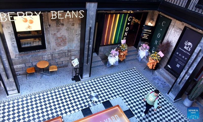 A woman takes pictures at Silverfish ST. in Qingdao, east China's Shandong Province, Nov. 1, 2022. In recent years, the old city area of Qingdao has started protective renovation of its historical and cultural communities, during which ancient buildings have been maintained and new industries and trades have brought vitality to the city.(Photo: Xinhua)