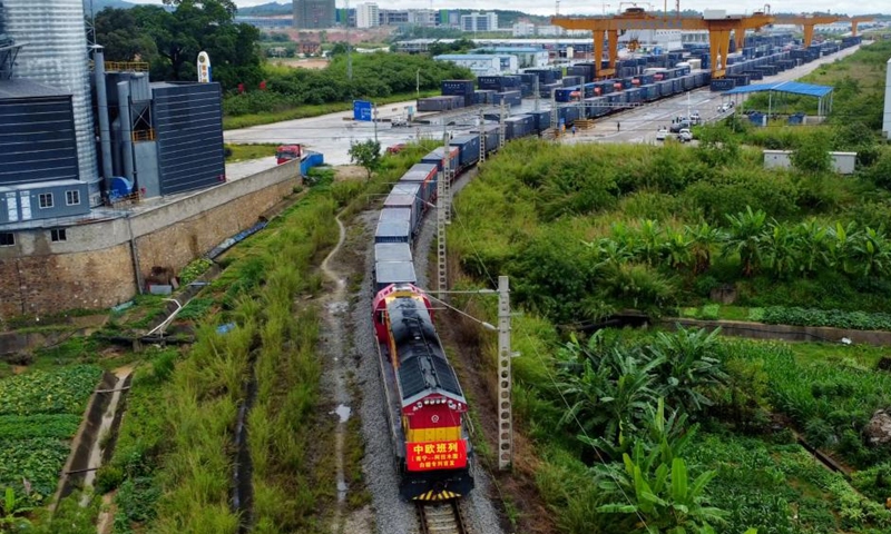 This aerial photo taken on May 15, 2022 shows a China-Europe freight train departing from Nanning, south China's Guangxi Zhuang Autonomous Region. In the first ten months of this year, the New International Land-Sea Trade Corridor saw 621,026 TEU containers transported by the railway intermodal freight trains, up 19.7 percent year on year.(Photo: Xinhua)