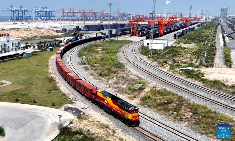 This aerial photo taken on Sept. 17, 2022 shows a freight train departing from Qinzhou Port in Qinzhou, south China's Guangxi Zhuang Autonomous Region. In the first ten months of this year, the New International Land-Sea Trade Corridor saw 621,026 TEU containers transported by the railway intermodal freight trains, up 19.7 percent year on year. (Photo: Xinhua)