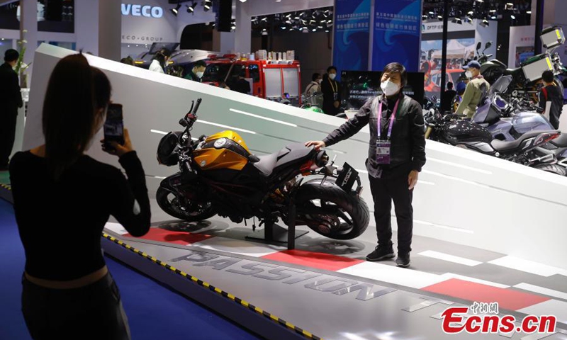 A staff member poses for photos with a motorcycle exhibited at the automobile exhibition area of the fifth China International Import Expo (CIIE) at the National Exhibition and Convention Center in Shanghai, Nov. 7, 2022. (Photo: China News Service/Yin Liqin)


