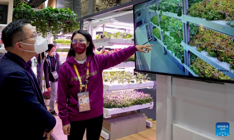 An exhibitor introduces agricultural technologies by showing the real-time scene of the monitor of a planting base at the food and agricultural products exhibition area of the fifth China International Import Expo (CIIE) in east China's Shanghai, Nov. 7, 2022. A seedling company displays vegetables growing on shelves to demonstrate new technologies of smart agriculture during the fifth CIIE in Shanghai.(Photo: Xinhua)