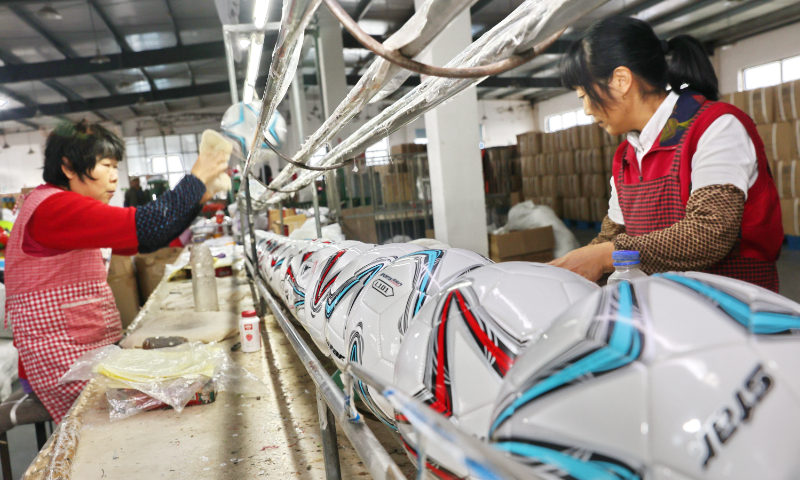 Workers make soccer balls at a factory in Nantong, East China's Jiangsu Province on No-vember 29, 2022. Amid the FIFA World Cup Qatar 2022, the factory's overseas orders surged by more than 50 percent year-on-year. Nantong is a soccer ball production hub, with more than 10 million footballs exported every year. Photo: cnsphoto 