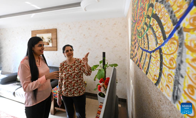 Gurmehar Singh and her mother talk about one of her paintings at her home in north China's Tianjin, Nov. 22, 2022.