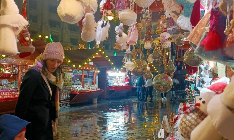 People visit the gift zone during the opening day of Bucharest's Christmas fair in Constitution Square, in front of the Parliament Palace, in Bucharest, capital of Romania, Nov. 20, 2022. (Photo by Cristian Cristel/Xinhua)