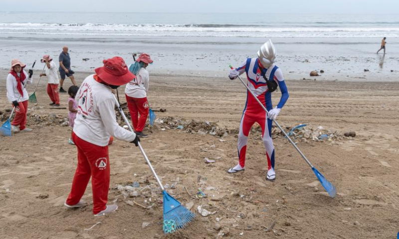 A volunteer wearing a costume of the Japanese fictional superhero Ultraman cleans trash with workers at Kuta Beach in Bali, Indonesia, Dec. 30, 2022. Photo: Xinhua
