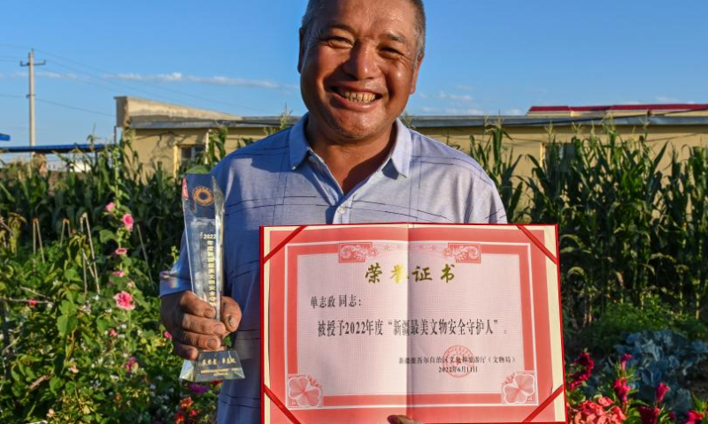 Shan Zhizheng demonstrates his honor certificate and trophy as Xinjiang's most beautiful conservator of cultural relics in Wenquan County in the Mongolian Autonomous Prefecture of Bortala, northwest China's Xinjiang Uygur Autonomous Region, July 27, 2022. (Xinhua/Hao Jianwei)