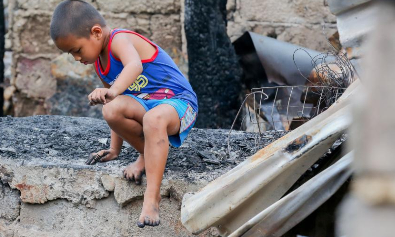 A boy is seen at his charred home after a fire at a slum area in Navotas City, the Philippines, Nov. 15, 2022. Photo: Xinhua