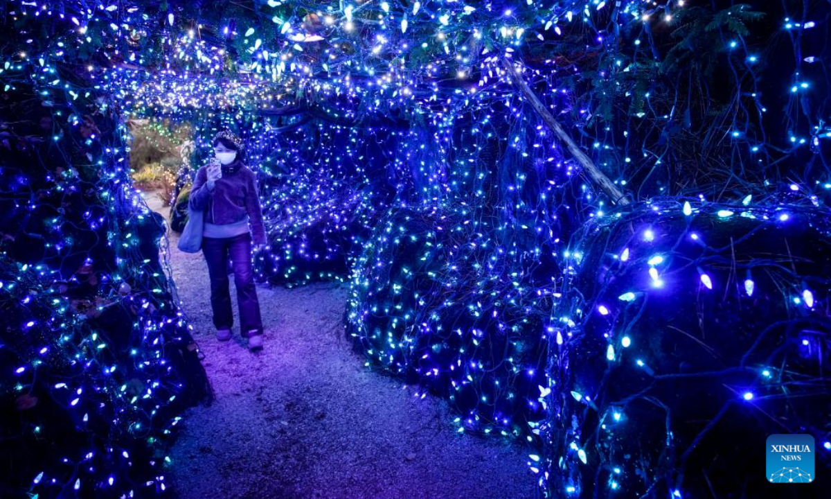A woman takes photos of the light decorations at the VanDusen Botanical Garden in Vancouver, British Columbia, Canada, Nov. 25, 2022. Featuring over a million lights in the 6.07-hectare VanDusen Botanical Garden, the 