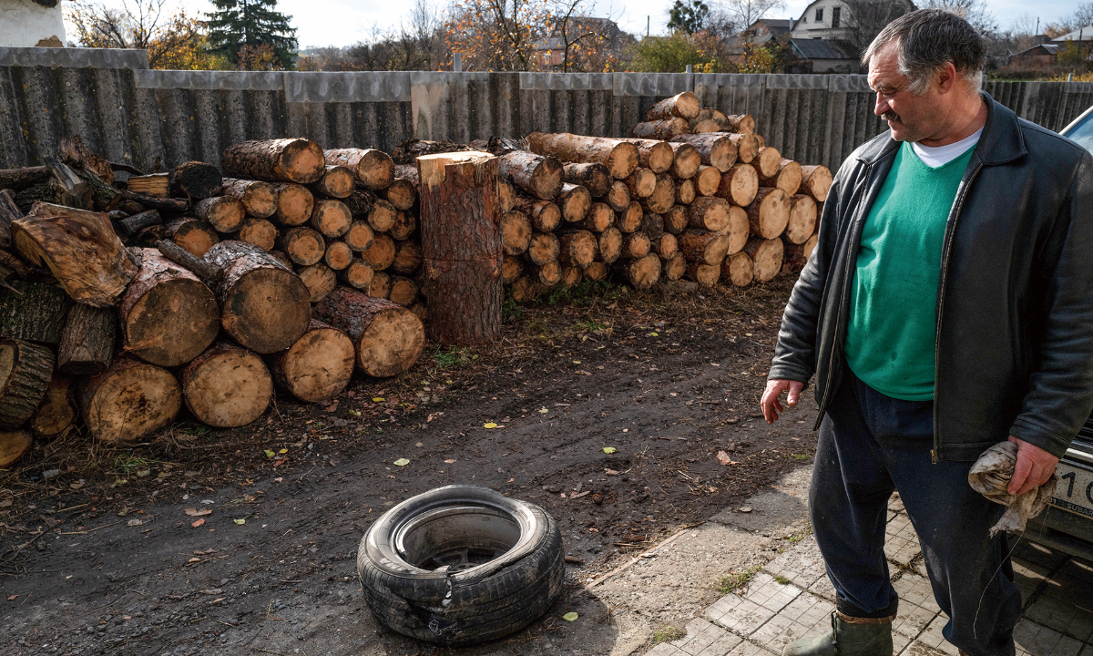 A man cuts and stores wood to heat up his home in the winter as their neighborhood still lacks gas utilities in Izyum, Ukraine on October 30, 2022. Photo: VCG