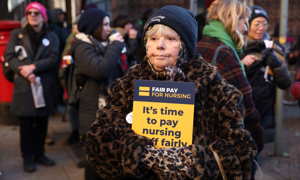 A supporter of nurses’ strike and National Health Service (NHS) holds a placard at a picket line outside St. Mary’s Hospital in west London, the United Kingdom on December 15, 2022. UK nurses staged an unprecedented one-day strike in order to get better wages and working conditions, despite warnings that it could put patients at risk. Photo: AFP