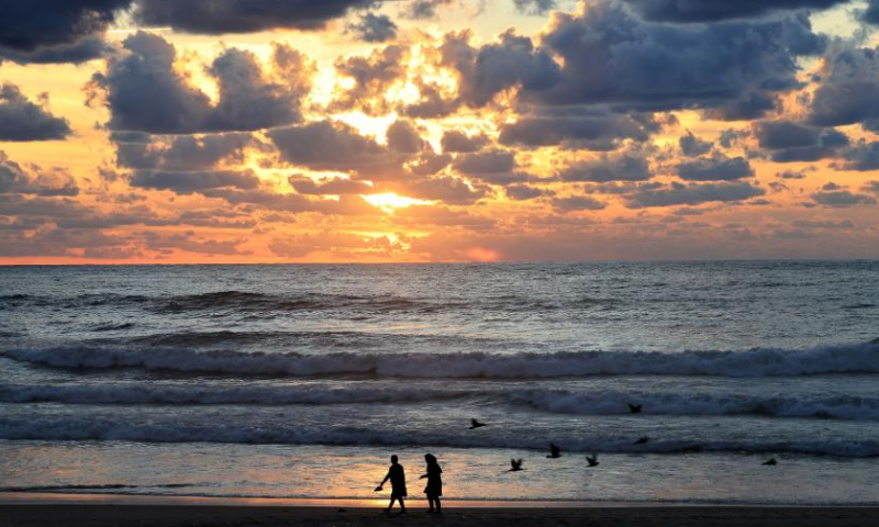 A couple walk at sunset on the beach of the Mediterranean Sea in Beirut, Lebanon, on Nov. 26, 2022. (Xinhua/Liu Zongya)